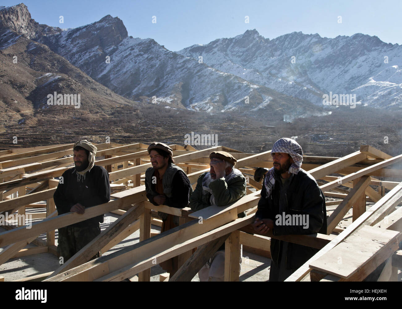 Afghan lavoratori edili per ascoltare i suggerimenti di un gruppo di ingegneri assegnati al Panjshir Provincial Reconstruction Team di ispezionare una ragazza progetto scuola nel distretto di Anaba del Panjshir provincia, in Afghanistan il 7 gennaio 05. L Operazione Enduring Freedom 237934 Foto Stock