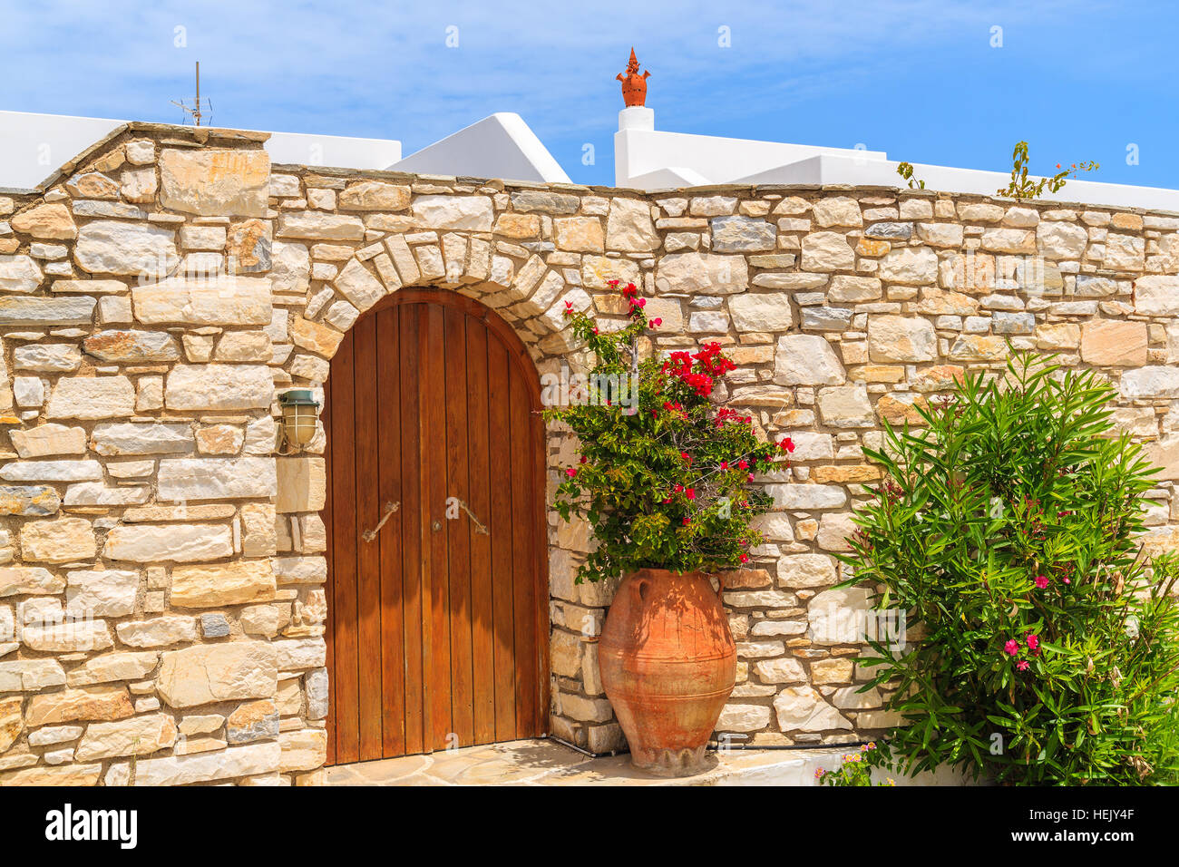 Porta di legno costruite nel muro di pietra e fiori in vaso, tipica architettura Greca sull isola di Paros, Grecia Foto Stock