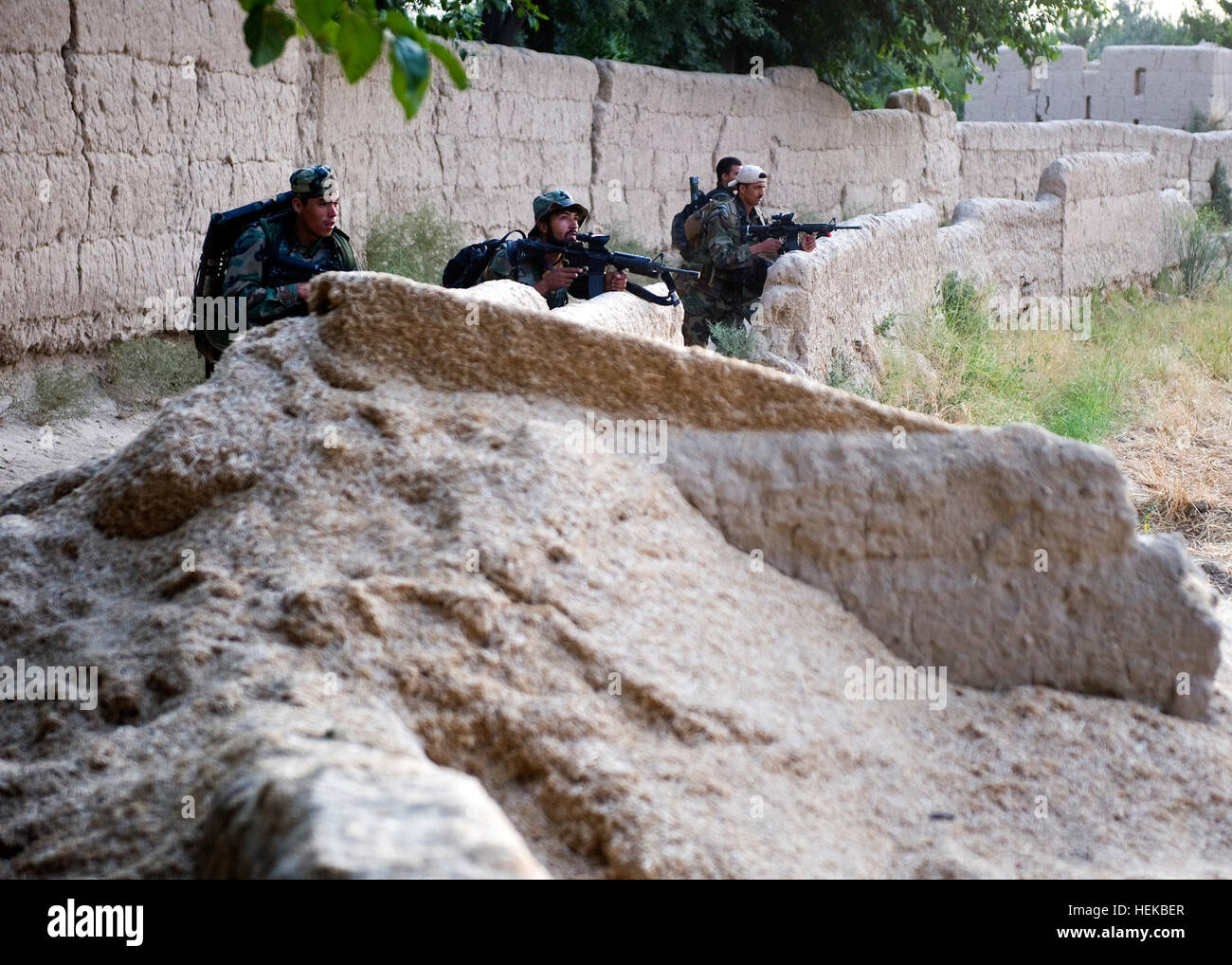 Afghan commandos, con l'Esercito nazionale afgano il 3° Commando Kandak, utilizzare una parete di copertura e nascondiglio dopo assunzione di tiro nemico durante un villaggio operazione di compensazione nel distretto di Zhari 6 Luglio, provincia di Kandahar, Afghanistan. Il commando, supportata da organi di servizio con le operazioni speciali Task Force - Sud, trovato e distrutto diversi caches costituito da gli esplosivi casalinghi e IED-materiali, nonché una cache di armi. Commandos, noi trovare scontri a fuoco, cache a Kandahar 425148 Foto Stock