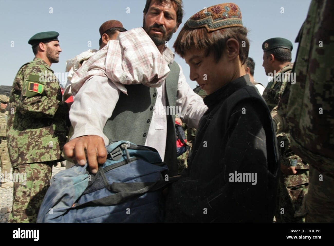 Ragazzi afghani salutare esercito nazionale afghano membri e soldati appartenenti a 2 miliardi, 87th INF nel quartiere Zharay, Afghanistan, Sett. 6, 2011. La scuola è destinata a dare bambini afgani alternativa di entrare nel commercio di droga o di lotta contro le forze della coalizione. (U.S. Foto dell'esercito da Cpl. Stephen J. Schmitz/RILASCIATO) Afghan ragazzo riceve il nuovo zaino 110906-A-SW743-003 Foto Stock