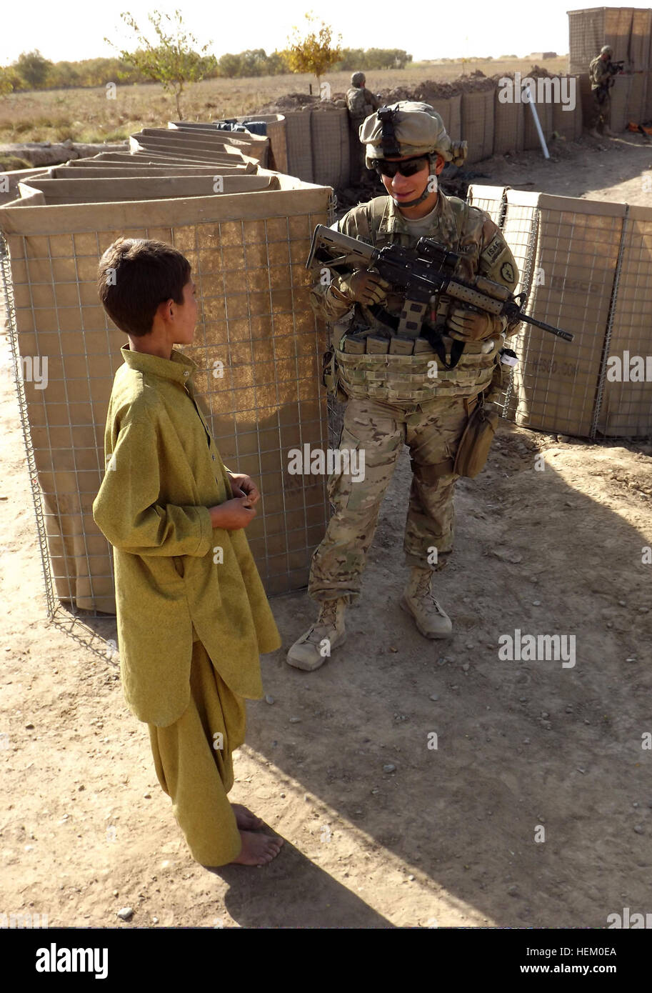 Stati Uniti Pfc dell'esercito. Mauro Rodriguez, un combattimento medic assegnato al primo battaglione, quinto reggimento di fanteria, 1° Stryker Brigade Combat Team, XXV divisione di fanteria, parla con un ragazzo afghano dal 1 dicembre 2011, durante una pattuglia di polizia nazionale afgana checkpoint nella provincia di Kandahar, Afghanistan. Rodriguez è stato distribuito in Afghanistan meridionale a sostegno dell'Operazione Enduring Freedom. (U.S. Esercito foto di Sgt. Thomas Duval/RILASCIATO) U.S. Pfc dell'esercito. Mauro Rodriguez, un combattimento medic assegnato al primo battaglione, quinto reggimento di fanteria, 1° Stryker Brigade Combat Team, XXV divisione di fanteria, parla con un ragazzo afgano Foto Stock