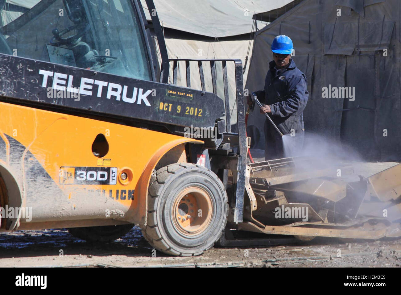Un appaltatore privato spruzza acqua per pulire parti di una miniera-resistenti, imboscata-veicolo protetto a inoltrare una base operativa gambo, provincia di Logar, Afghanistan, Marzo 14, 2012. (U.S. Esercito foto di Spc. Tia Sokimson) in avanti di una base operativa gambo 120314-A-RR514-035 Foto Stock