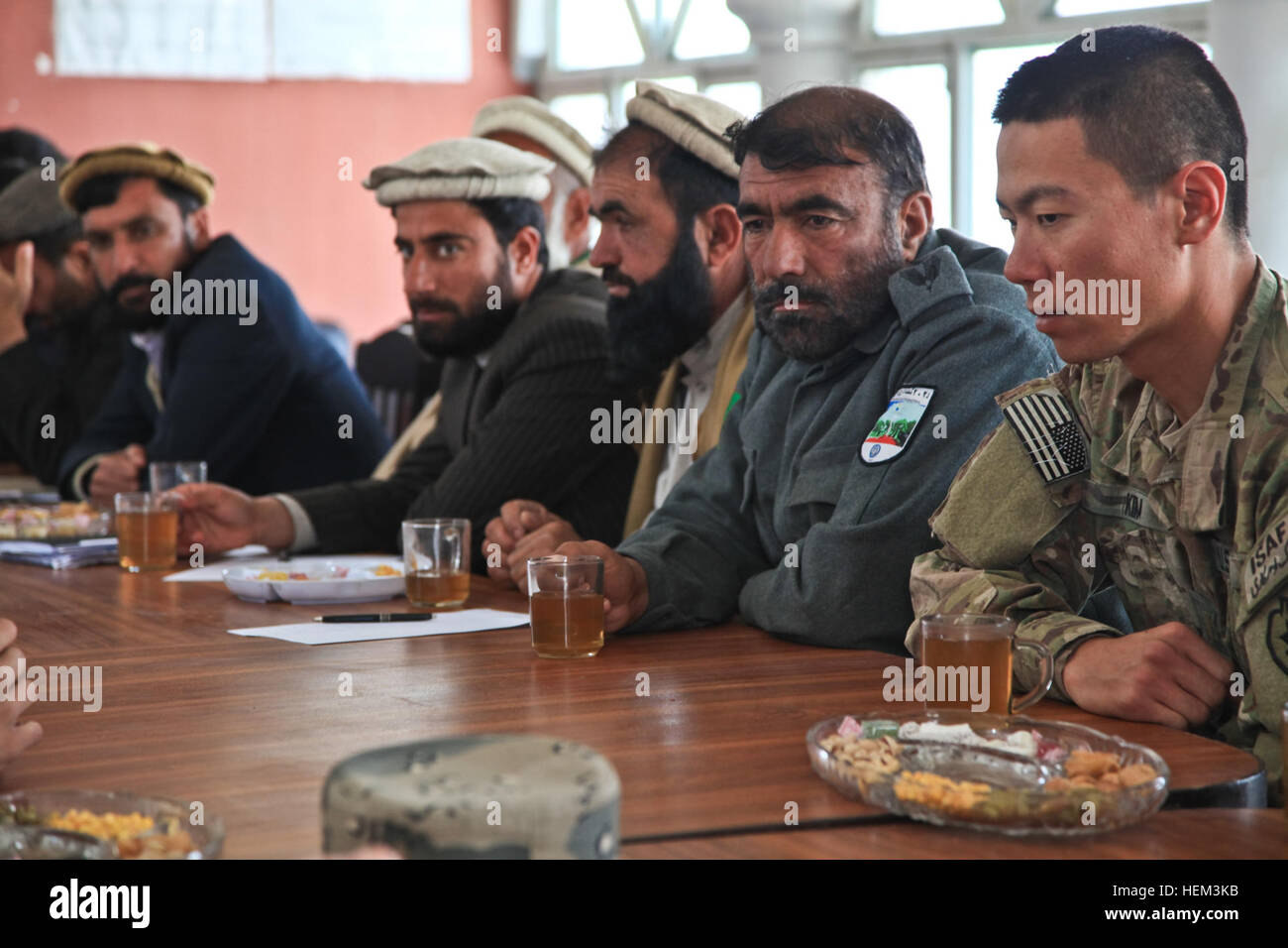 Stati Uniti Esercito 2 Lt. Teodoro Kim, da Honolulu, Hawaii, servendo con il primo plotone, una truppa, terzo squadrone, 4° reggimento di cavalleria, XXV divisione di fanteria, Task Force Raider, siede accanto a un afghano di polizia in uniforme stati durante una Shura, Nazyan distretto, provincia di Nangarhar, Afghanistan, Marzo 15, 2012. Lo scopo del tasto innesto Leader era quello di ottenere la familiarizzazione di quartiere e di una nuova leadership. Tasto innesto leader 120315-A-LP603-034 Foto Stock