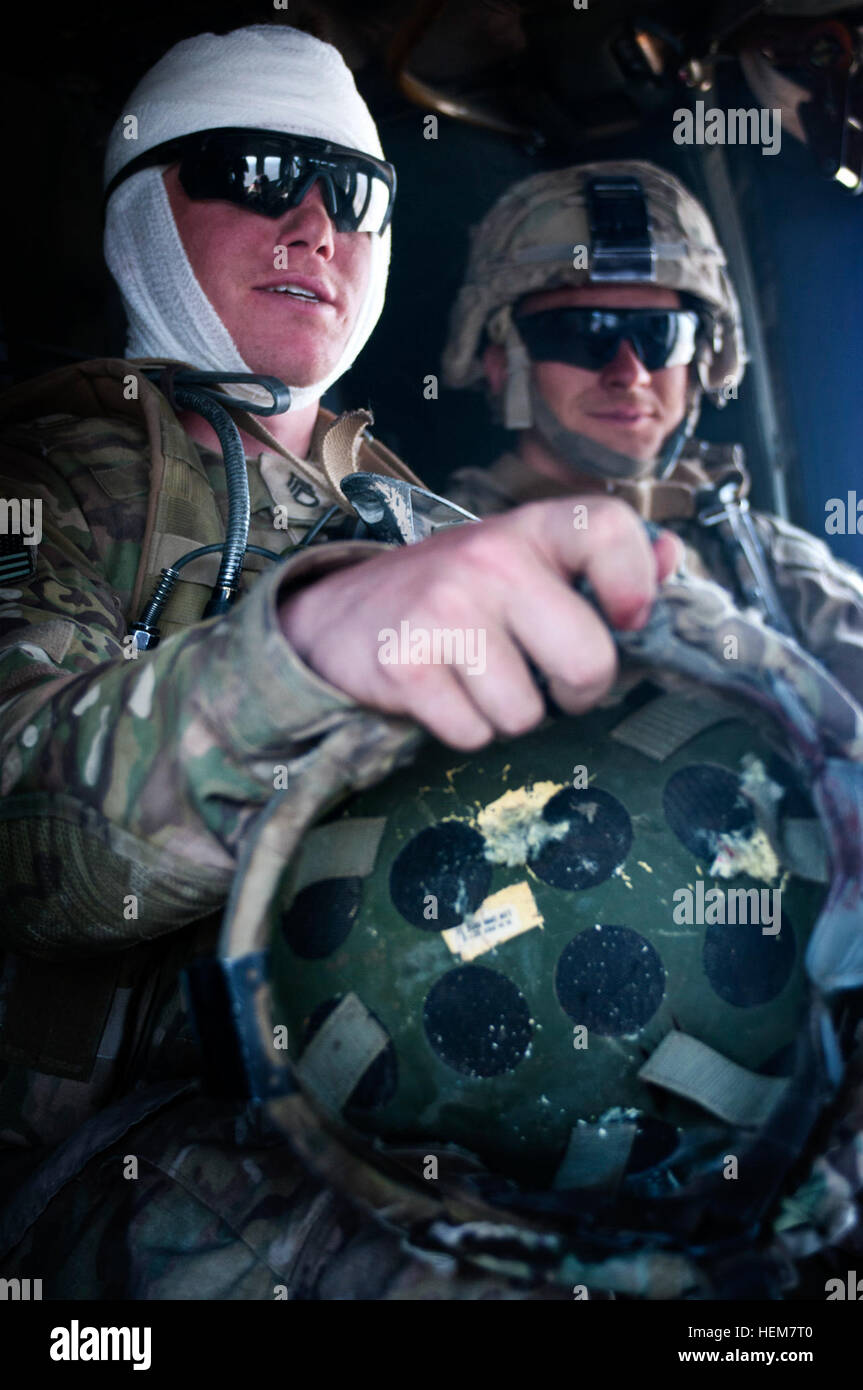 Il personale Sgt. Ryan Stumpff di Fort Bragg, N.C., pone in bendaggi tenendo il suo casco danneggiato. Pfc. Michael Halberg del campo di battaglia, nello Stato di Washington, accompagna Stumpff in una Black Hawk Medevac Helicopter poco dopo essere stato salvato tramite paranco l'estrazione dal lato di una montagna in provincia Khowst, Afghanistan. Stumpff è stato colpito alla testa da un ribelle, ma il proiettile penetrato nel retro del suo casco, sfiorato la sua testa ed esce dalla parte anteriore. Halberg quindi uccisi ribelli e proteggendo la sua battaglia buddy. La coppia della XXV divisione di fanteria soldati fuori di Fort Richardson, Alaska, divenne strand Foto Stock