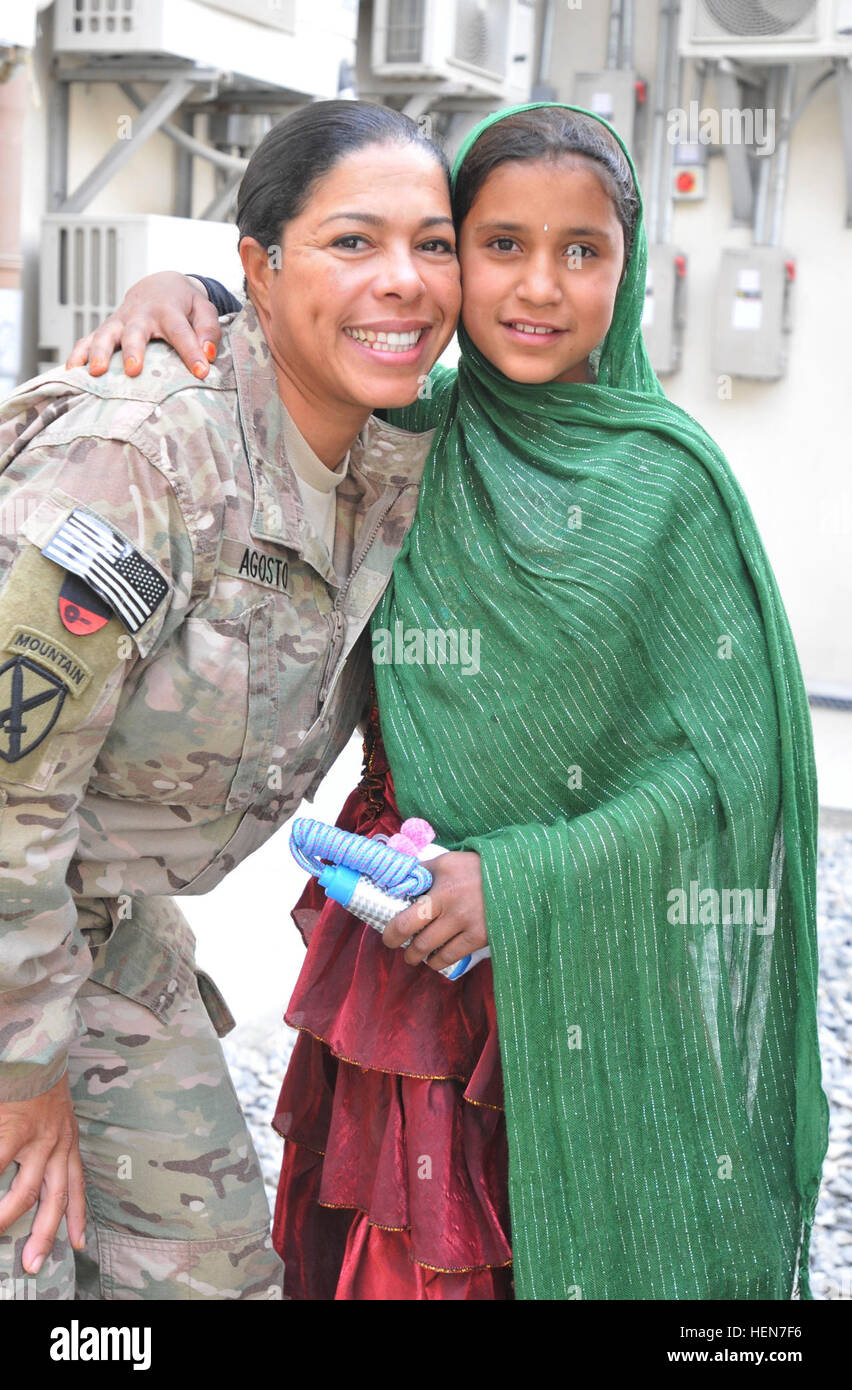 Lt. Col. Nelsa Agosto, un residente di Orlando, Florida, 1° Theatre Supporto comando, abbracci una giovane ragazza afgana, presso le donne afghane's Bazaar, nuovo composto di Kabul, Afghanistan, su Ott. 23, 2013. Le donne afghane e i bambini venuti a NKC per vendere casa-spun artigianato e altro ancora, il bazar è una opportunità per le donne e i bambini per aiutare a sostenere le loro famiglie attraverso la vendita di souvenir afghano. (U.S. Foto dell'esercito da Sgt. 1. Classe Timoteo Prato, 1° Theatre supporto comando degli affari pubblici/rilasciato a Chitter chatter di giovani I bambini riempiono l'aria come nuovo composto di Kabul, le donne afgane%%%%%%%%E2%%%%%%%%8 Foto Stock