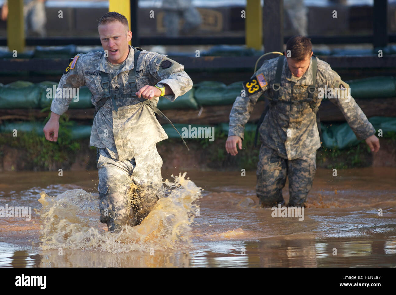 I ranger dell'esercito assegnati alla Guardia Nazionale del Texas e della Pennsylvania corrono attraverso una fossa d'acqua durante il percorso ad ostacoli Malvesti a Camp Rogers, Fort Benning, Georgia. L'evento fa parte del 31° concorso annuale Best Ranger Competition, test di resistenza, lavoro di squadra e abilità tattiche dei concorrenti. Foto Stock