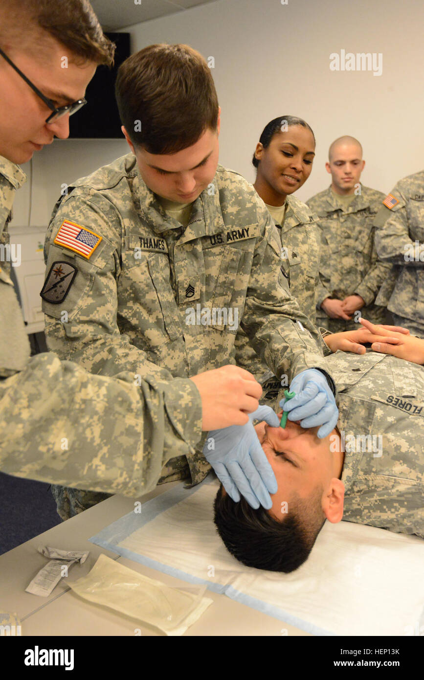 Stati Uniti Il personale dell'esercito Sgt. La Giordania Thames con 128Signal Company, 39th battaglione di segnale, attentamente introduce il tubo endotracheale nasofaringeo in SPC. Darrel Flores' naso durante il combattimento life saver porzione dell'unità del Comandante trimestrale del primo tempo alla formazione, presso il Quartier generale supremo delle potenze alleate in Europa, Belgio, Dic 10, 2014. (U.S. Esercito foto di Visual Information Specialist Pascal Demeuldre-Released) segnale 39th combat life saver 141210-A-RX599-054 Foto Stock