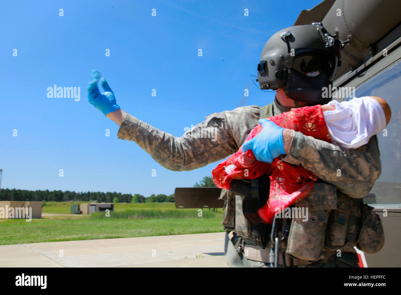 Stati Uniti Esercito personale di riserva Sgt. John Autry, 1° Battaglione, 214th reggimento di aviazione, Johnstown, Pa., detiene simulato un neonato mentre si utilizzano segnali a mano alla guida di un team di medici in modo sicuro verso la piazzola di atterraggio in avanti base operativa della libertà durante il Global Medic a Fort McCoy, Wis., 19 giugno 2015. La simulazione del neonato è stato clinicamente evacuato ad un supporto di combattimento ospedale con una cancrena infezione. Global Medic è il premier campo medico evento di formazione nel dipartimento della difesa ed è l'unico giunto esercizio accreditati concepito, pianificato ed eseguito da riserva di esercito di soldati che sono parte del Foto Stock