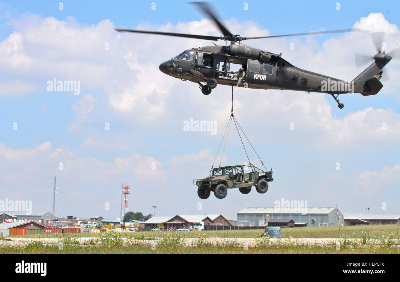 Un UH-60 Black Hawk elicottero porta un Humvee durante imbracare il carico di formazione di familiarizzazione di Luglio 6, 2015, a Camp Bondsteel in Kosovo. La formazione è stata condotta per aiutare a familiarizzare la multinazionale in arrivo battaglia Group-East soldati con imbracatura le operazioni di carico e le procedure. (U.S. Esercito foto di Sgt. Erick Yates, multinazionale battaglia Group-East) sicuro e sicuro, MNBG-E soldati sul treno imbracatura operazioni di carico 150706-A-RN359-049 Foto Stock