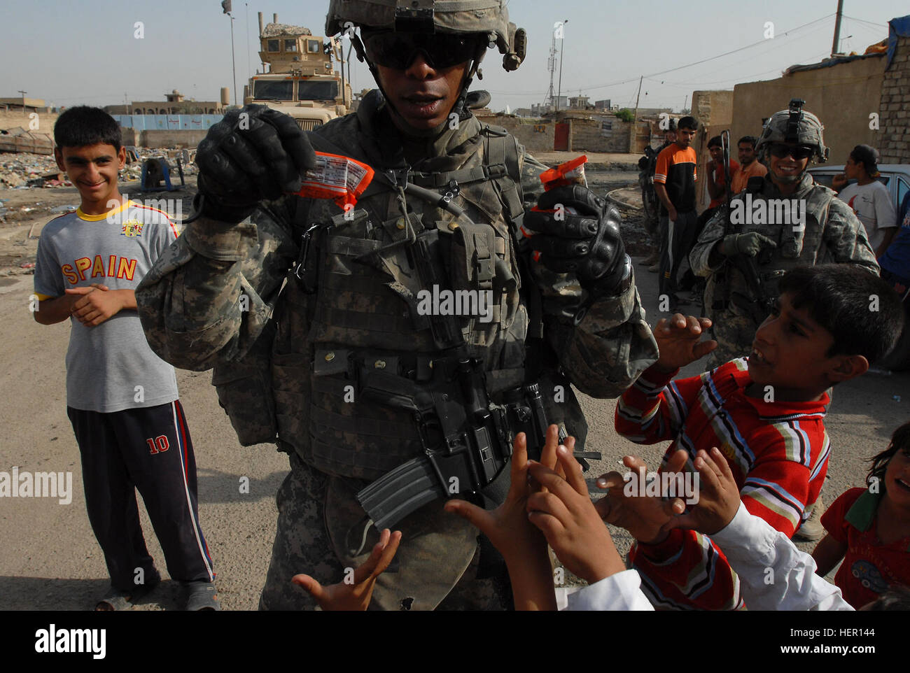 Stati Uniti Army Spc. Chris Jackson, nativo di Washington D.C., un fante, per una società, 1° Battaglione, 6° Reggimento di Fanteria, 2° Brigata Team di combattimento, 1° Divisione Corazzate, attualmente fissata al 3° Brigata Team di combattimento, 4a divisione di fanteria, mani Reese's pezzi caramelle ai bambini di un povero quartiere di Sadr City quartiere di Bagdad, 13 ottobre, 2008. I soldati sono stati passare fuori libero palloni da calcio, biscotti, caramelle ai bambini di vicinato. Il quartiere è in soldati area operativa. Mentre Jackson e i suoi compagni soldati sono ben noti nel settore, è Jackson Foto Stock