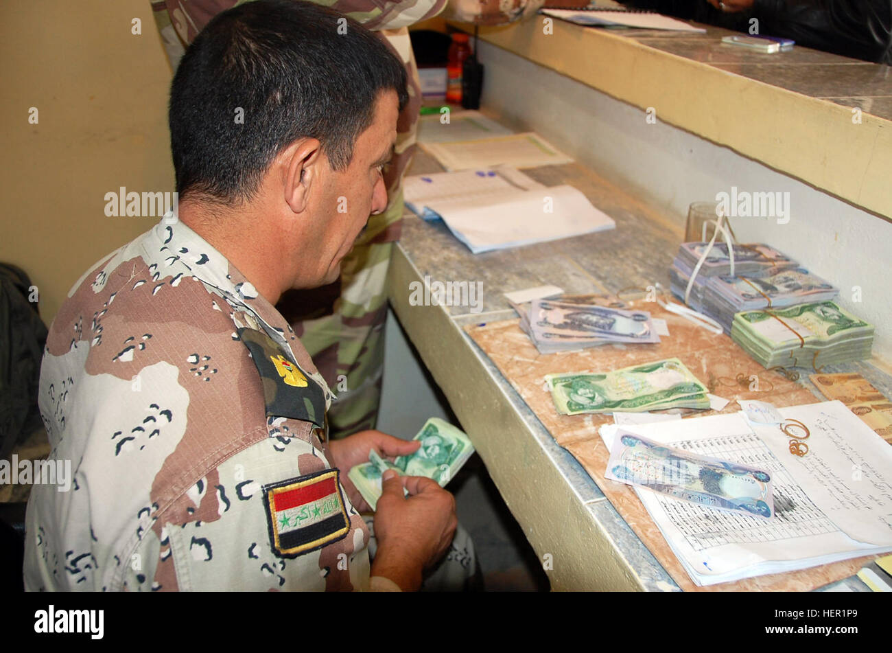 Un esercito iracheno pmo conteggi dinari iracheni per un figli dell Iraq payday in Tarmiyah, nov. 10. Le attività di giorno di paga ha segnato il primo del suo genere in quanto il governo dell'Iraq assunte responsabilità fiscale per il programma di SOI. Figli di Iraq pagato dall esercito iracheno a nord-ovest di Bagdad 128465 Foto Stock