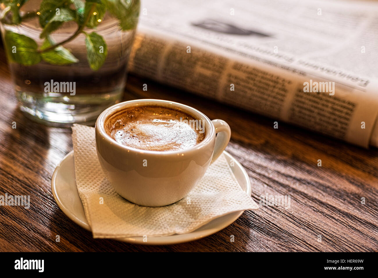 Tazza di caffè, acqua e giornale su un tavolo di legno. Buona mattina o pausa caffè concetto. Foto Stock