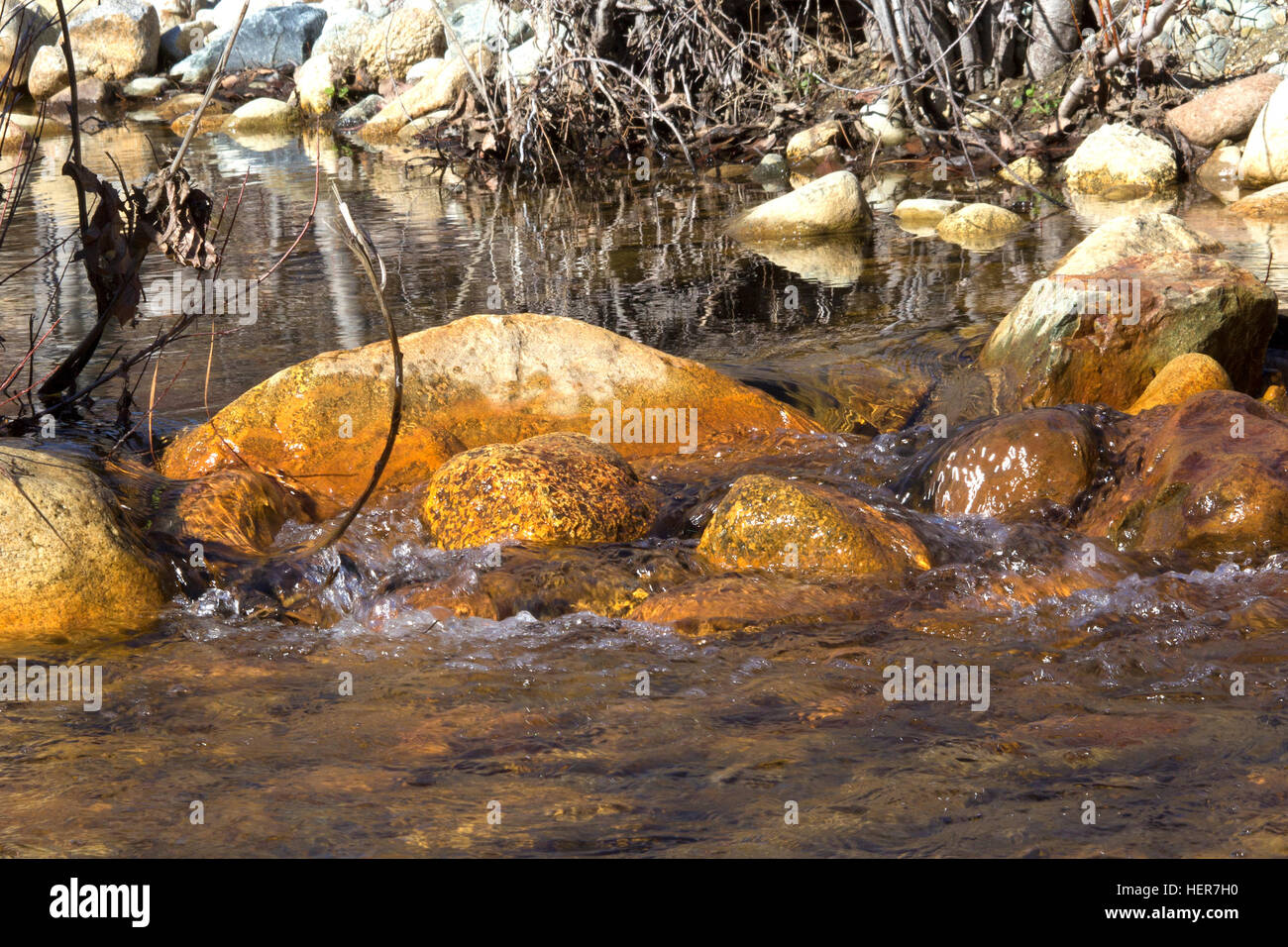 L'acqua che scorre intorno a rocce gialle Foto Stock