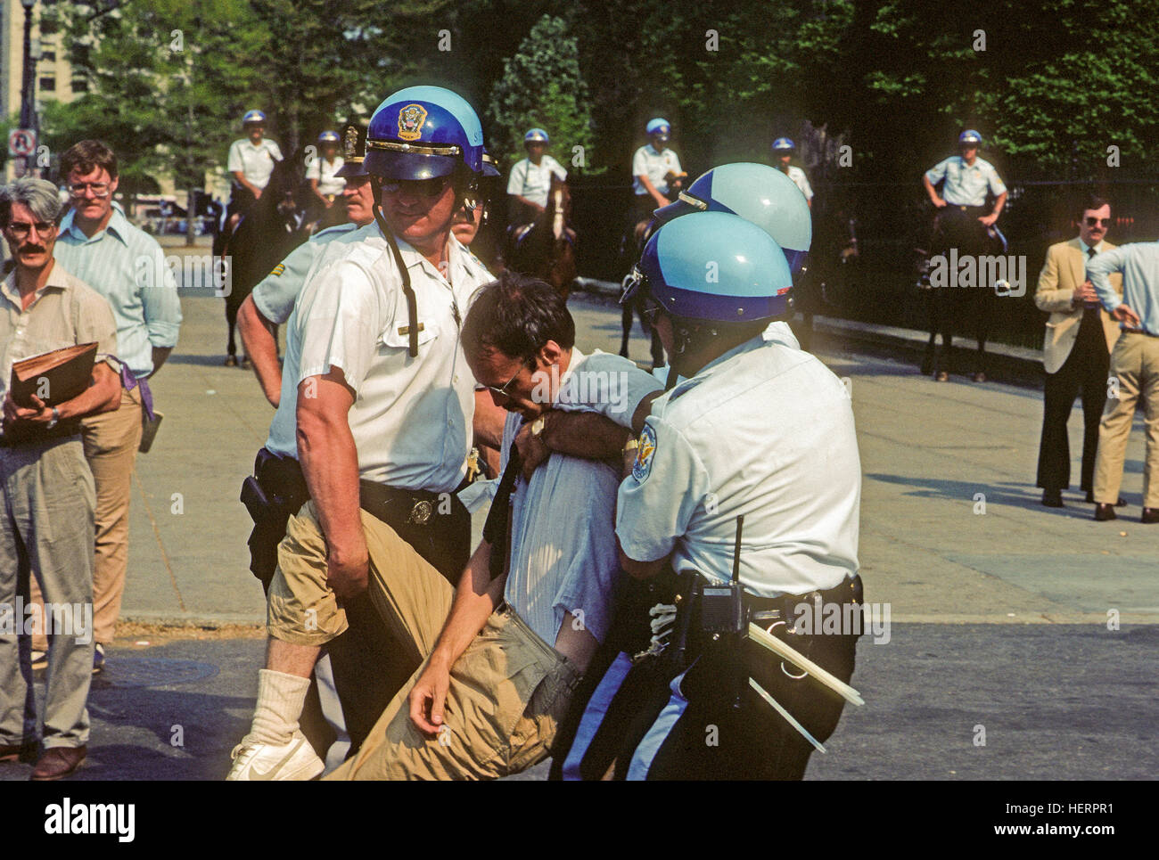 Washington, DC, Stati Uniti d'America, Aprile 1985 Noi Park gli ufficiali di polizia hanno per trascinare e trasportare antiwar manifestanti dal davanti della porta di nord-ovest della Casa Bianca. I manifestanti sedette bloccando la porta e sono stati messi agli arresti. Credito: Mark Reinstein Foto Stock