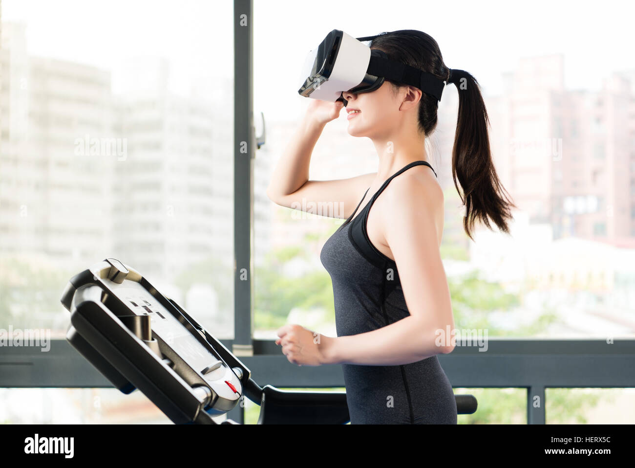 Bellezza donna asiatica in esecuzione il tapis roulant dalla realtà  virtuale. VR occhiali cuffie dispositivo. all'interno della palestra sfondo  Foto stock - Alamy