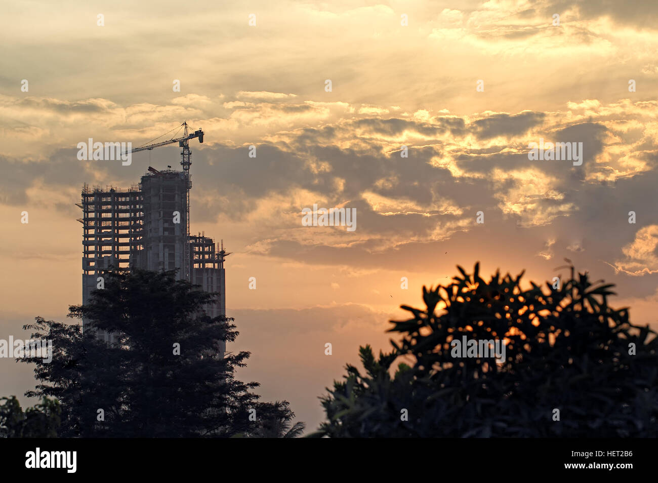 Silhouette di un edificio a torre in costruzione utilizzando i moderni metodi di costruzione, contro il sole al tramonto e nuvole Foto Stock