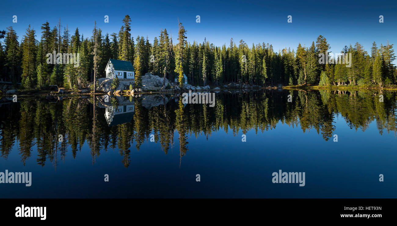 Lago di zanzara, California. Sierra lago con un riflesso speculare della foresta, cielo blu, alberi e cabine. Foto Stock