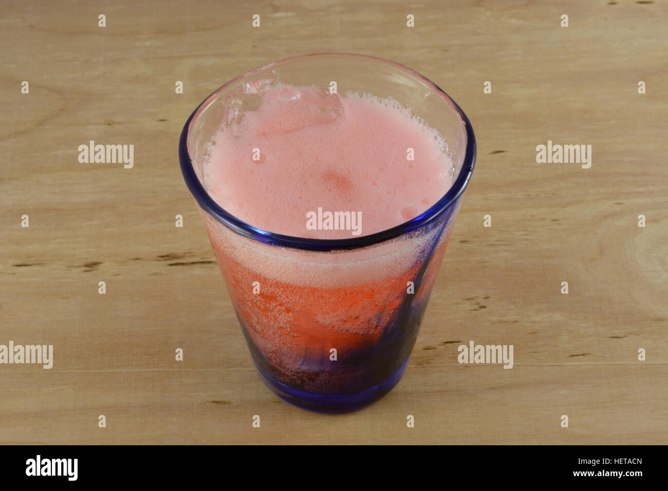 La formazione di bolle gassose cherry lime soda pop nel bicchiere sul tavolo Foto Stock