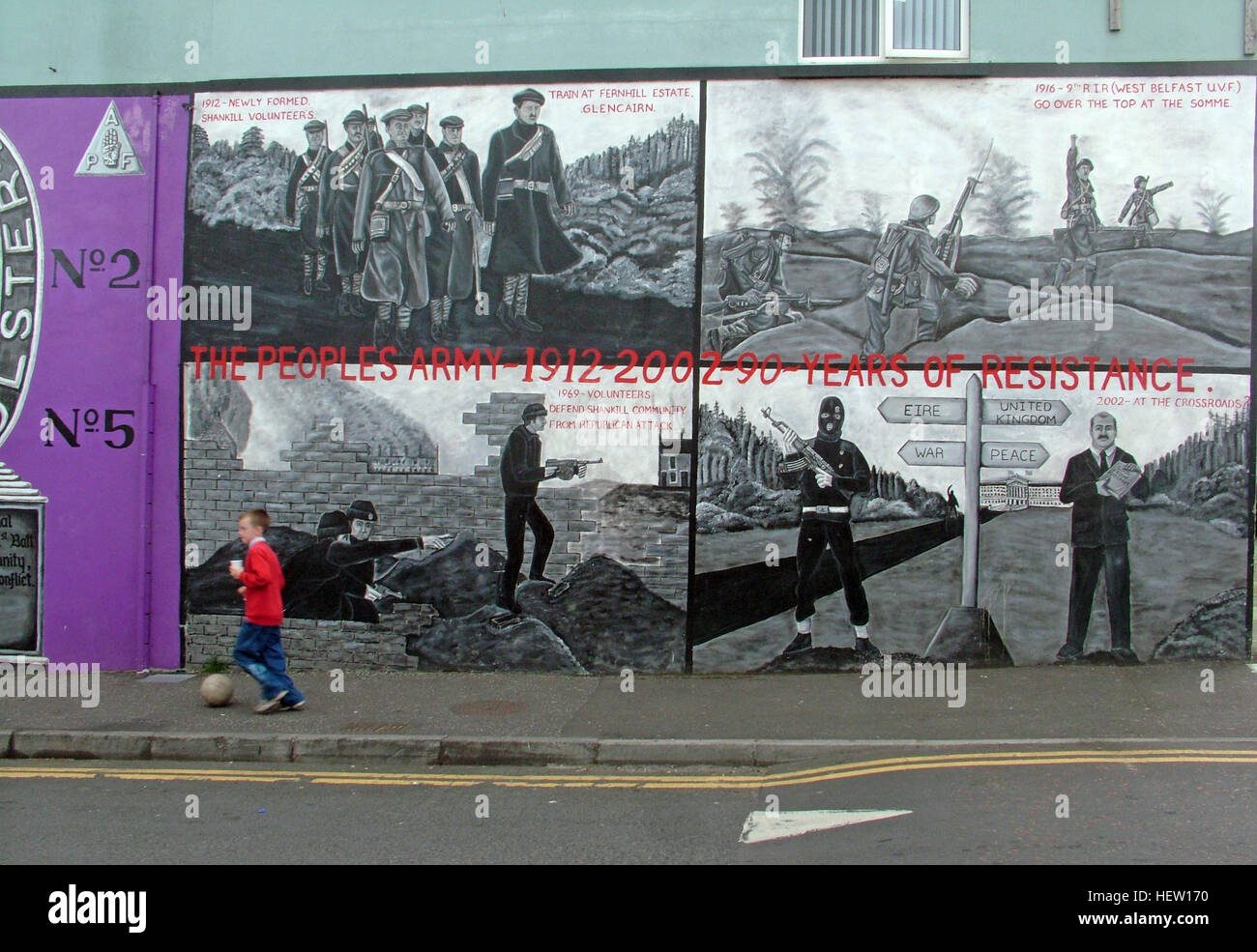 Shankill Road murale -90 anni di resistenza, parte occidentale di Belfast, Irlanda del Nord, Regno Unito, con ragazzo calci calcio Foto Stock