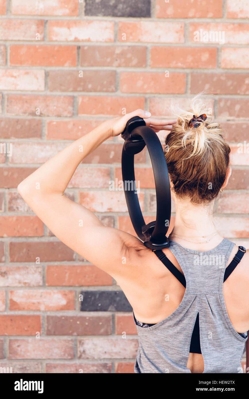 Vista posteriore della donna utilizzando pilates anello tonificante Foto Stock