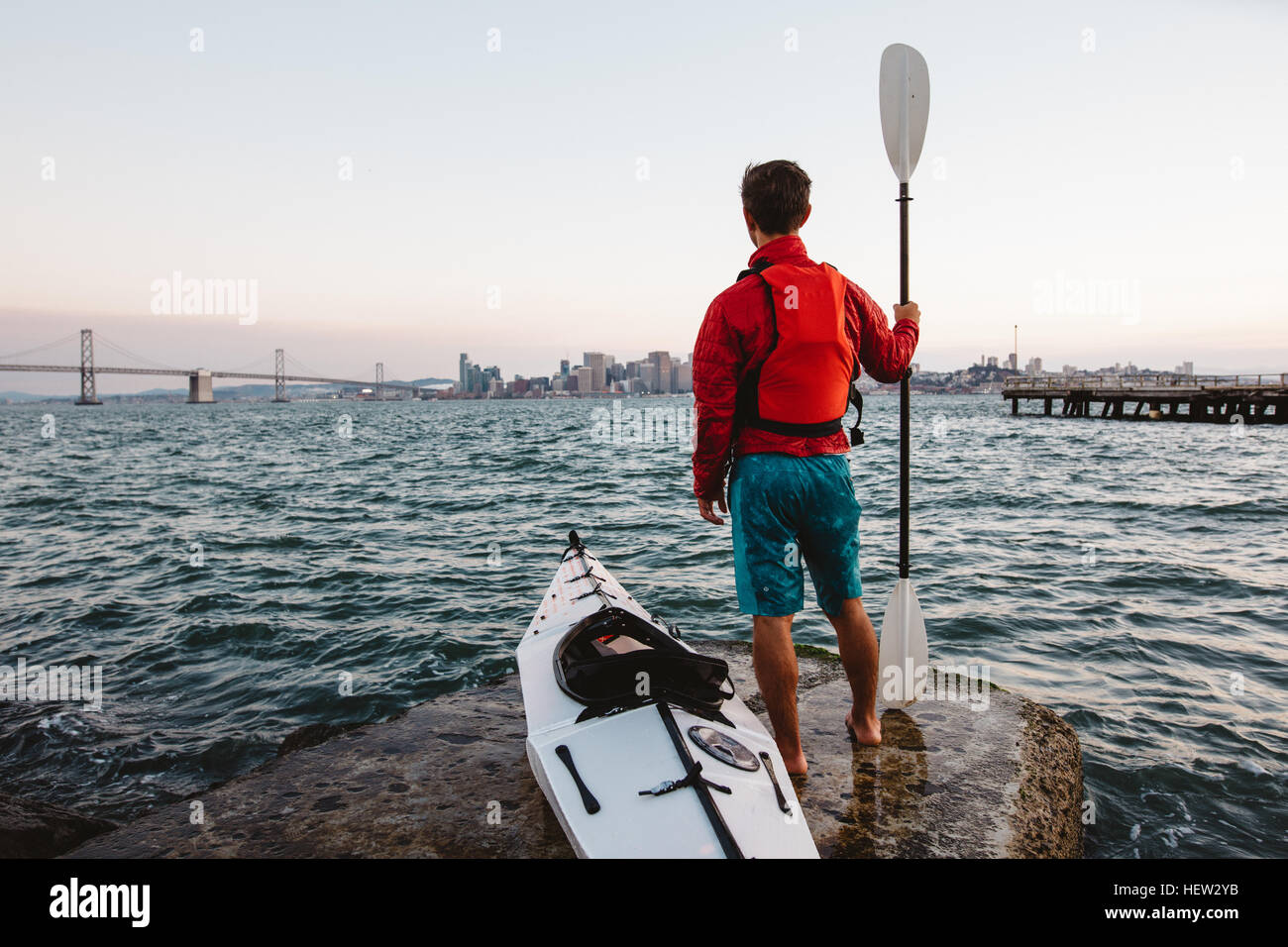 Uomo con il kayak e oar, guardando al mare, San Francisco, California, Stati Uniti d'America Foto Stock