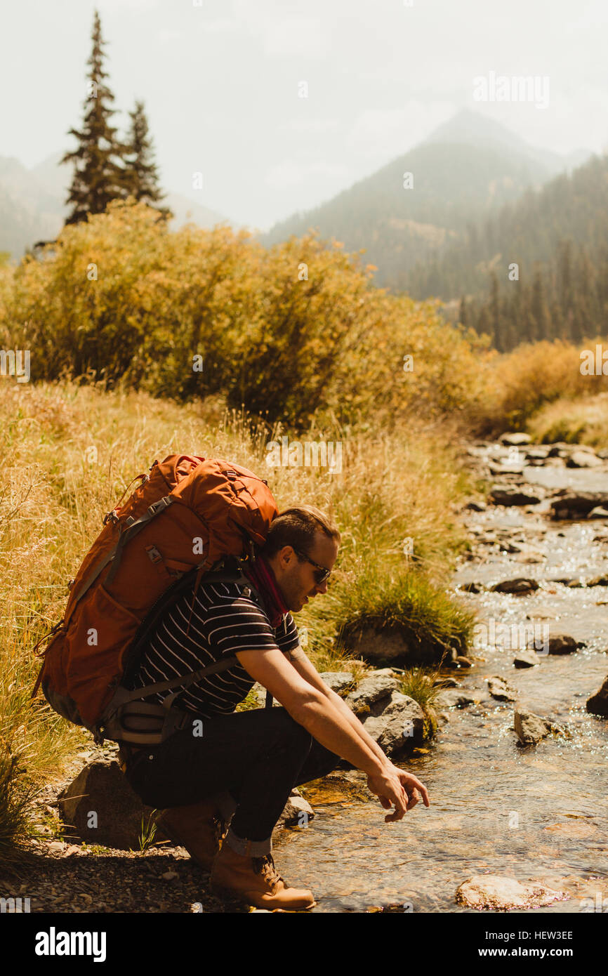 Uomo che indossa uno zaino, seduto da creek, minerale re, Sequoia National Park, California, Stati Uniti d'America Foto Stock