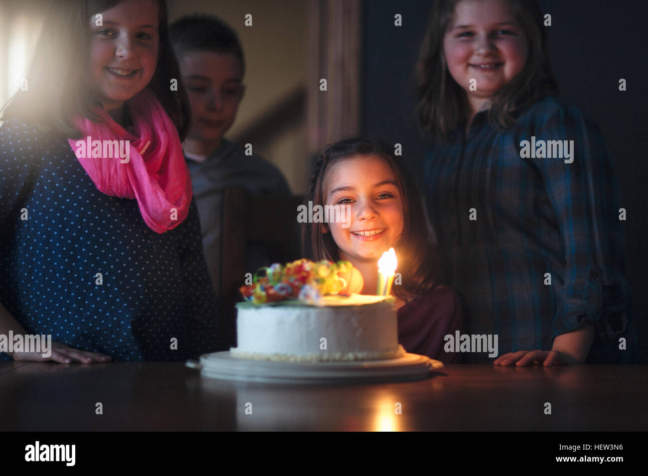 Ragazza con torta di compleanno circondato da amici Foto Stock