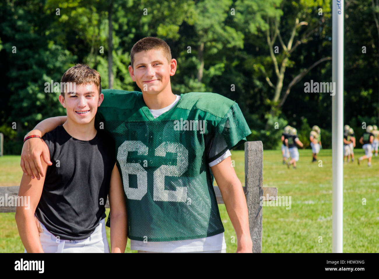 Ritratto maschile teenage giocatore di football americano con il braccio intorno all amico sul campo da gioco Foto Stock