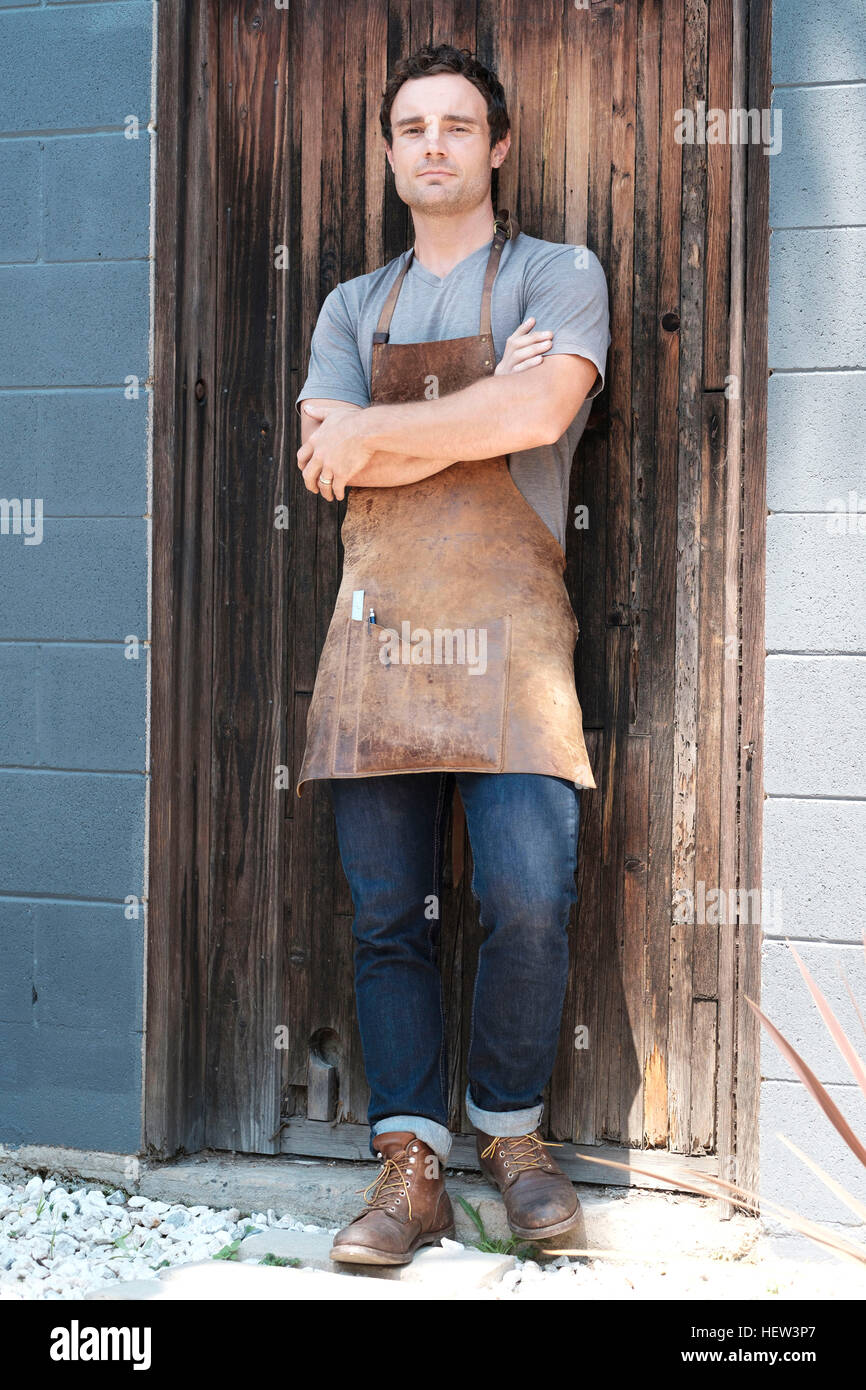 Carpenter al di fuori della sua officina con le braccia incrociate Foto Stock