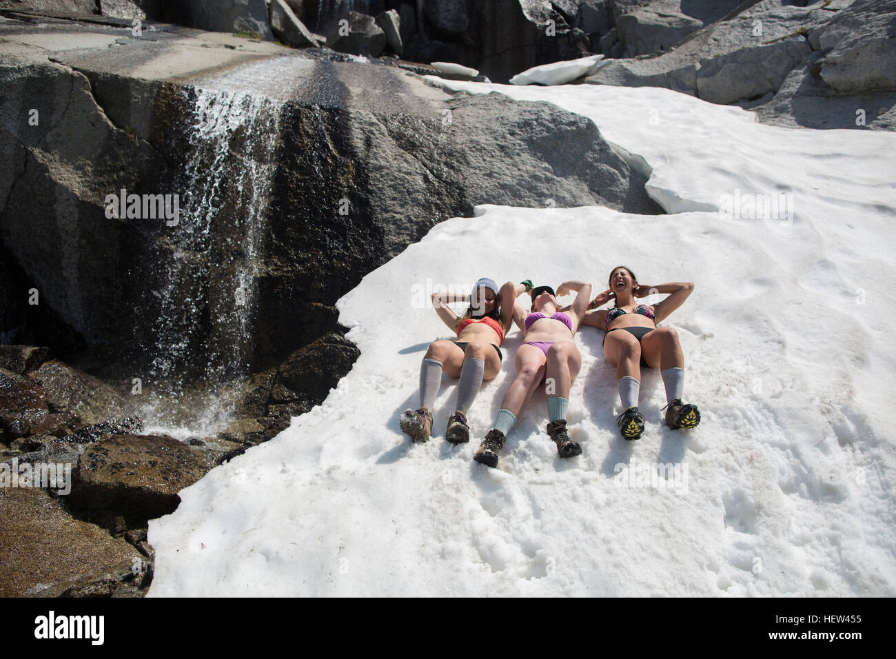 Tre giovani donne che indossano bikini, giacente in neve il incantesimi, Alpine Lakes Wilderness, Washington, Stati Uniti d'America Foto Stock