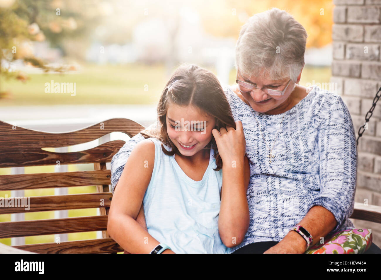 Nonna e nipote seduta sul portico swing, ridendo Foto Stock