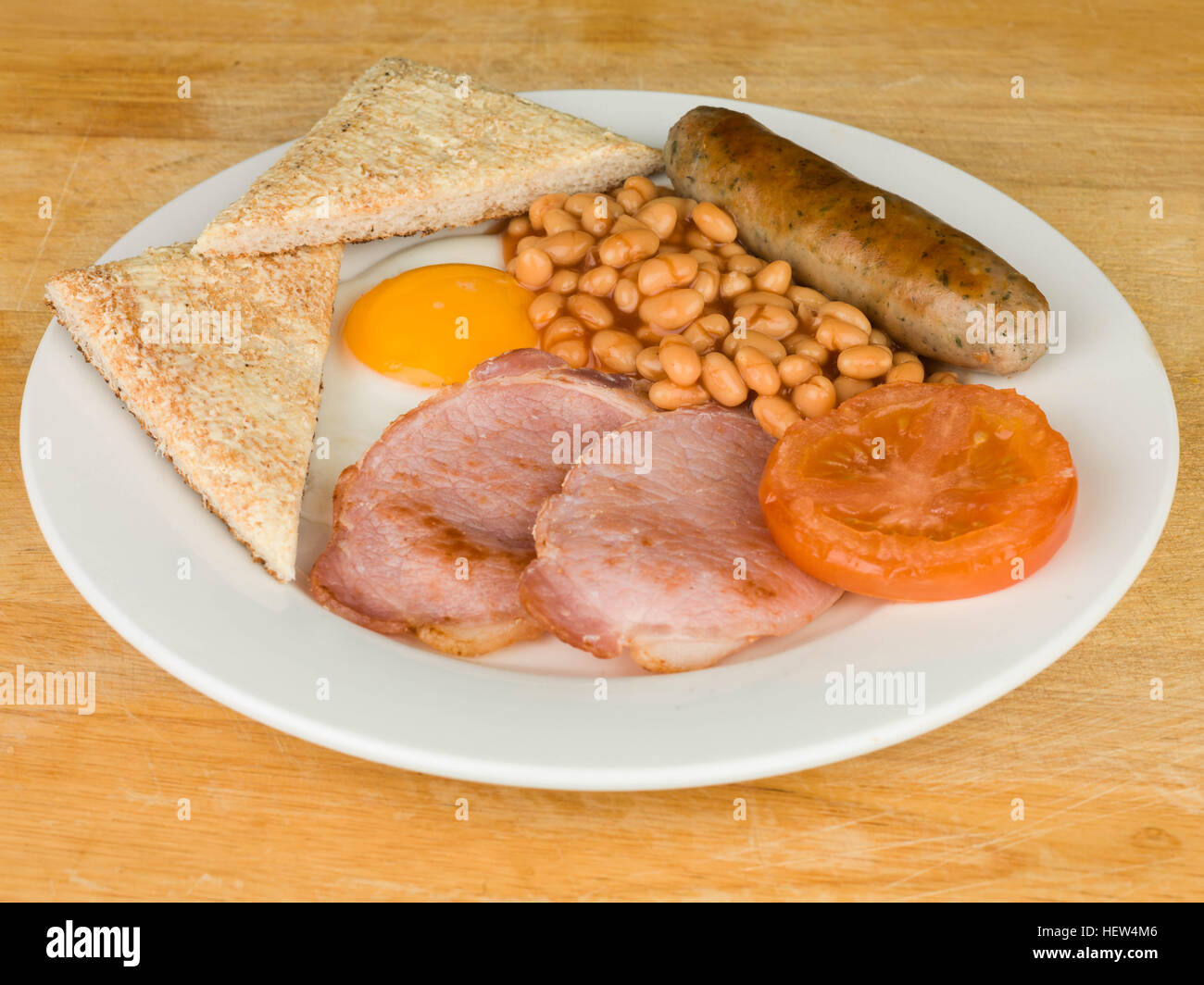 La completa prima colazione inglese uova pancetta salsiccia fagioli al forno e pomodoro servita su una piastra bianca Foto Stock