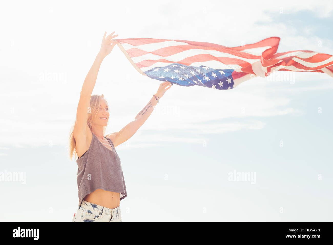 Donna con braccia alzate tenendo bandiera americana Foto Stock