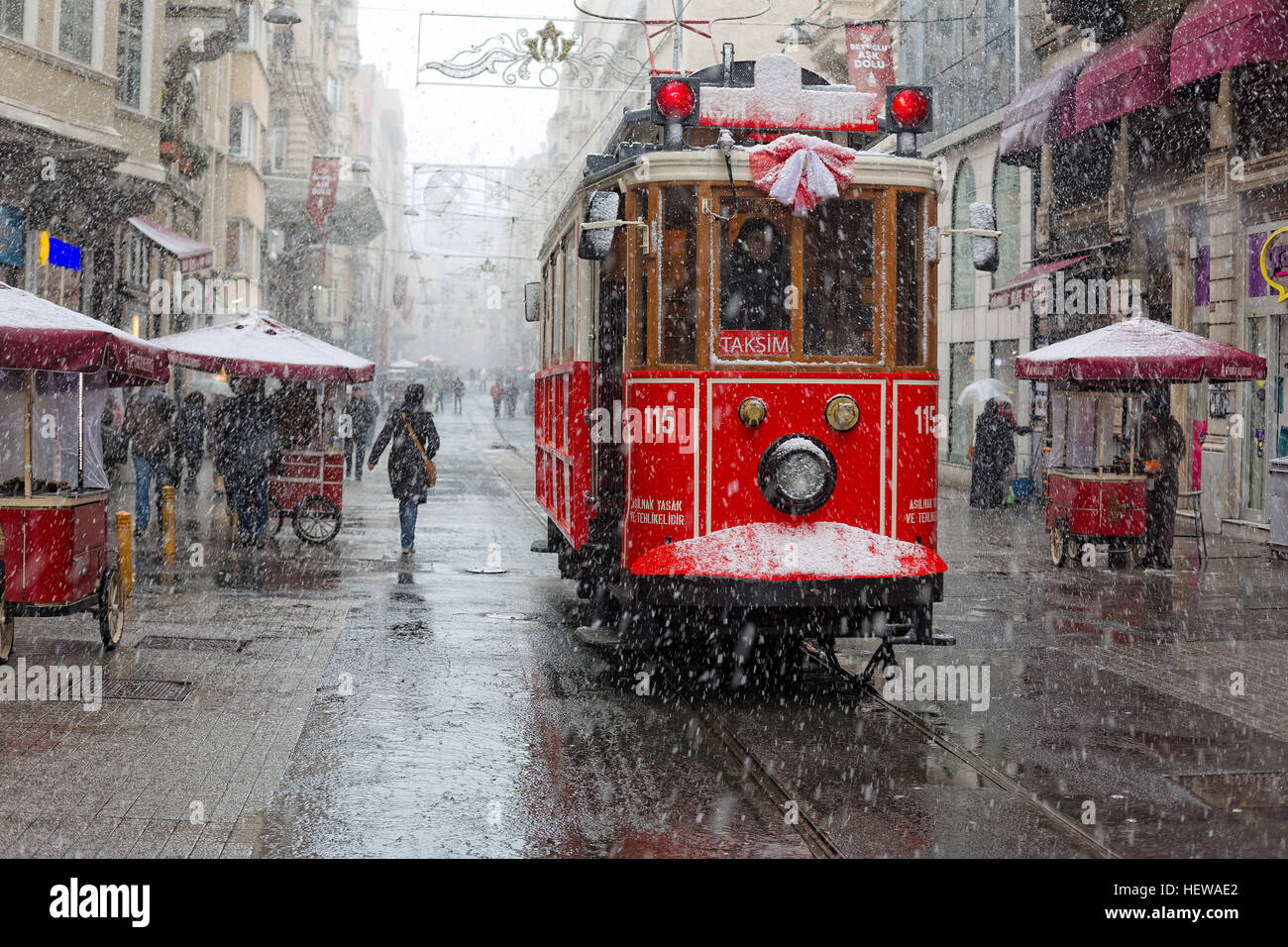 Tram Nostalgico di Istanbul e bagel venditore in istiklal street e la gente a piedi su Via Istiklal sotto la neve a Istanbul Foto Stock