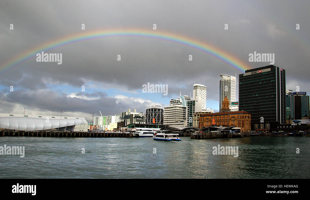 Una vista vivace del lungomare di Auckland con un arcobaleno, scattato con una fotocamera SONY, che enfatizza lo skyline colorato e il paesaggio urbano della zona. Foto Stock
