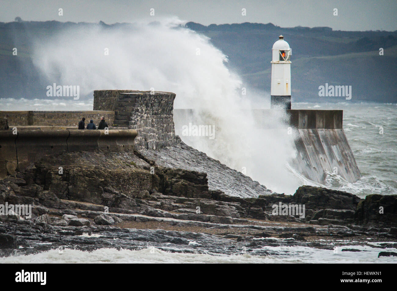 La gente guarda onde infrangersi sul porto muro a Porthcawl, nel Galles del Sud, come il Regno Unito e in Irlanda sono appoggiati per l arrivo di tempesta Barbara, con venti di 90mph prevede di pastella in alcune parti del paese. Foto Stock