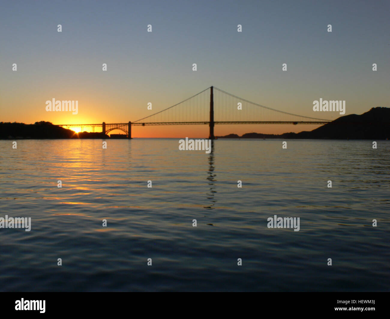 Il Golden Gate Bridge al tramonto, con l'iconico ponte sospeso rosso-arancione che si staglia contro un cielo vibrante. Questa fotografia cattura la bellezza architettonica del ponte e lo splendido sfondo naturale della baia di San Francisco. Foto Stock