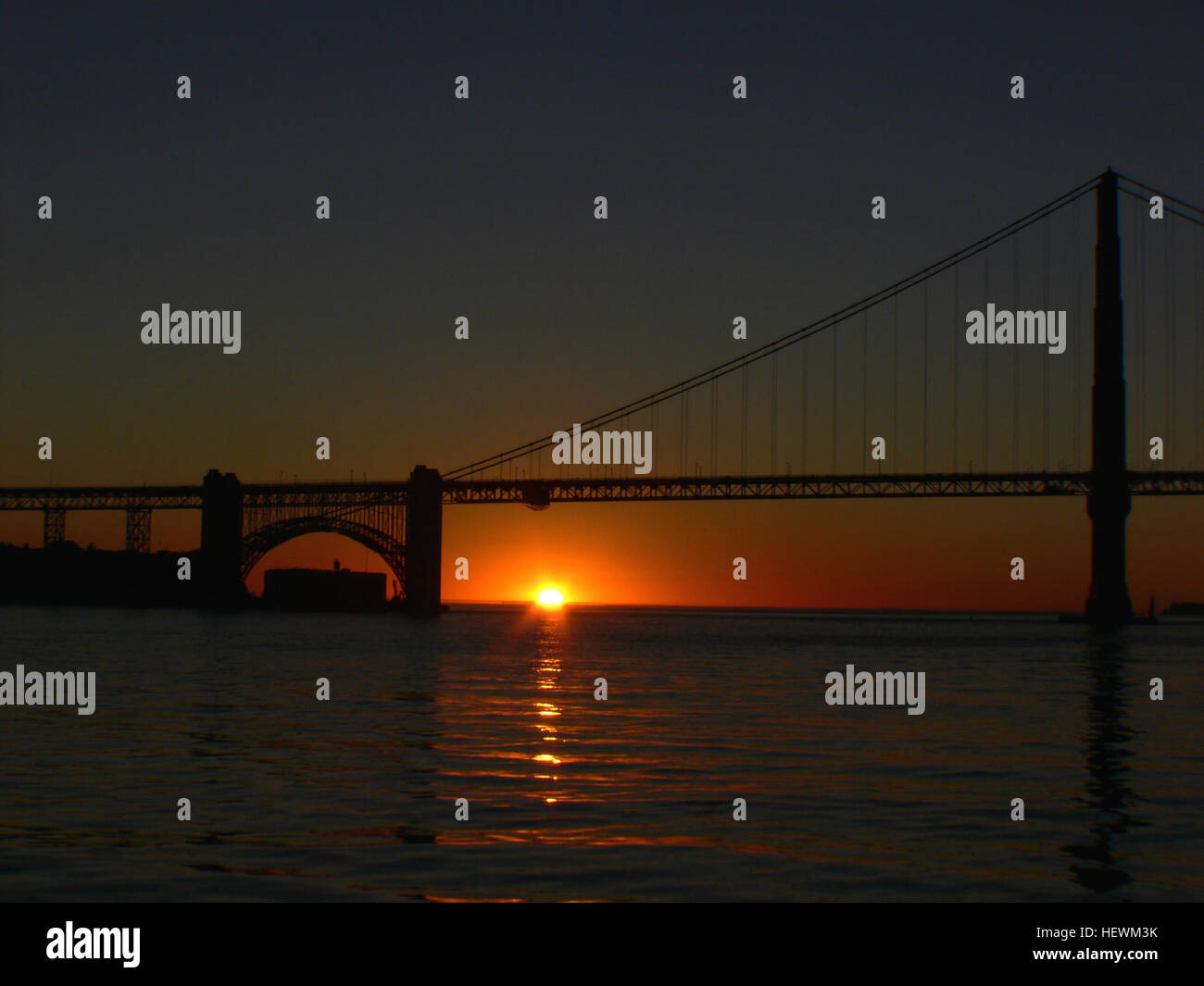 Il Golden Gate Bridge di San Francisco durante il tramonto. La fotografia cattura l'iconica struttura con il caldo bagliore del sole che tramonta sullo sfondo, evidenziando il suo design unico e il suo significato per la città di San Francisco. Foto Stock