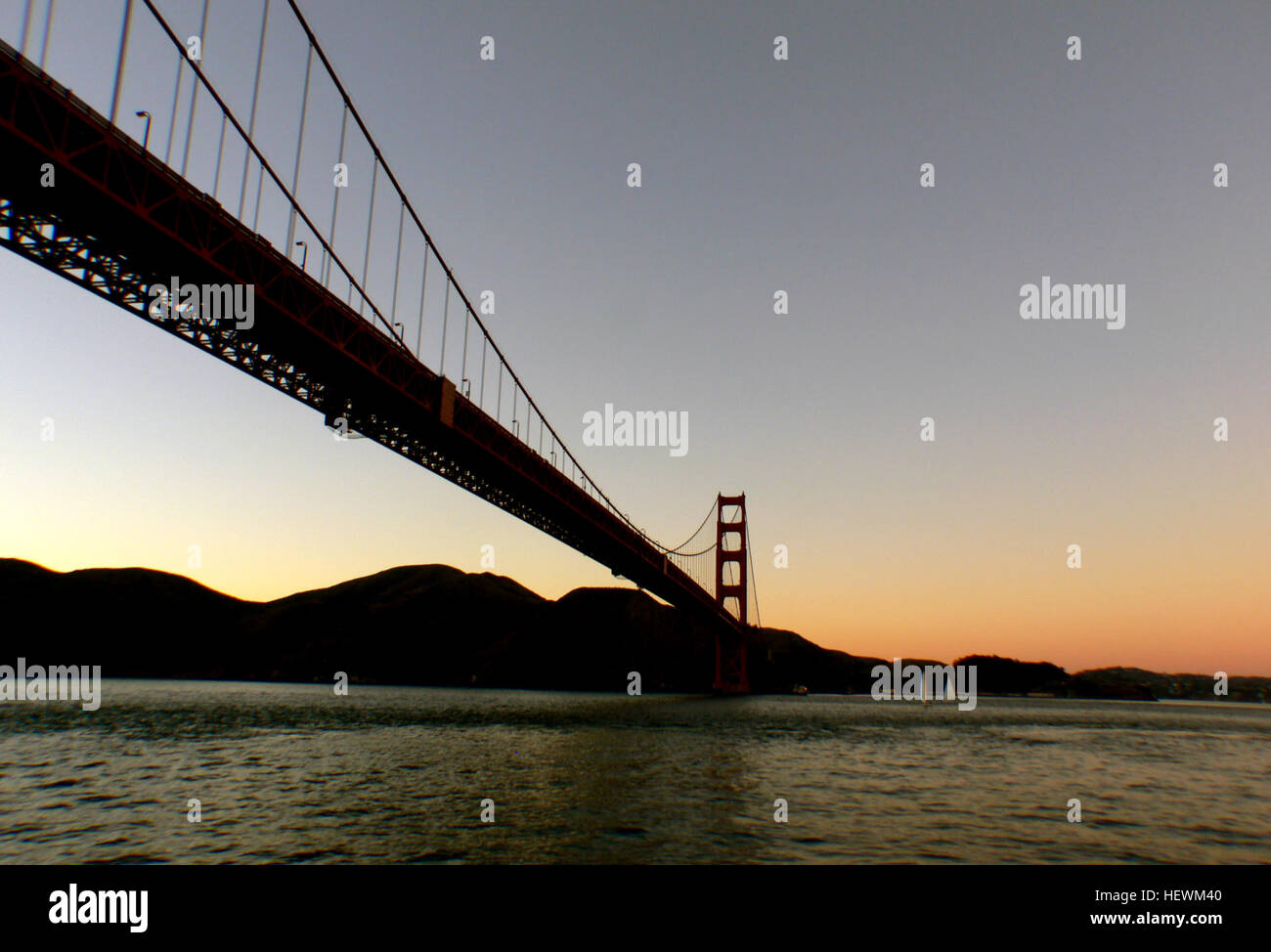 Il Golden Gate Bridge, uno dei punti di riferimento più rappresentativi di San Francisco, viene mostrato durante il tramonto. La fotografia cattura le viste mozzafiato del ponte che si staglia contro i colori vibranti del sole che tramonta sulla baia. Foto Stock