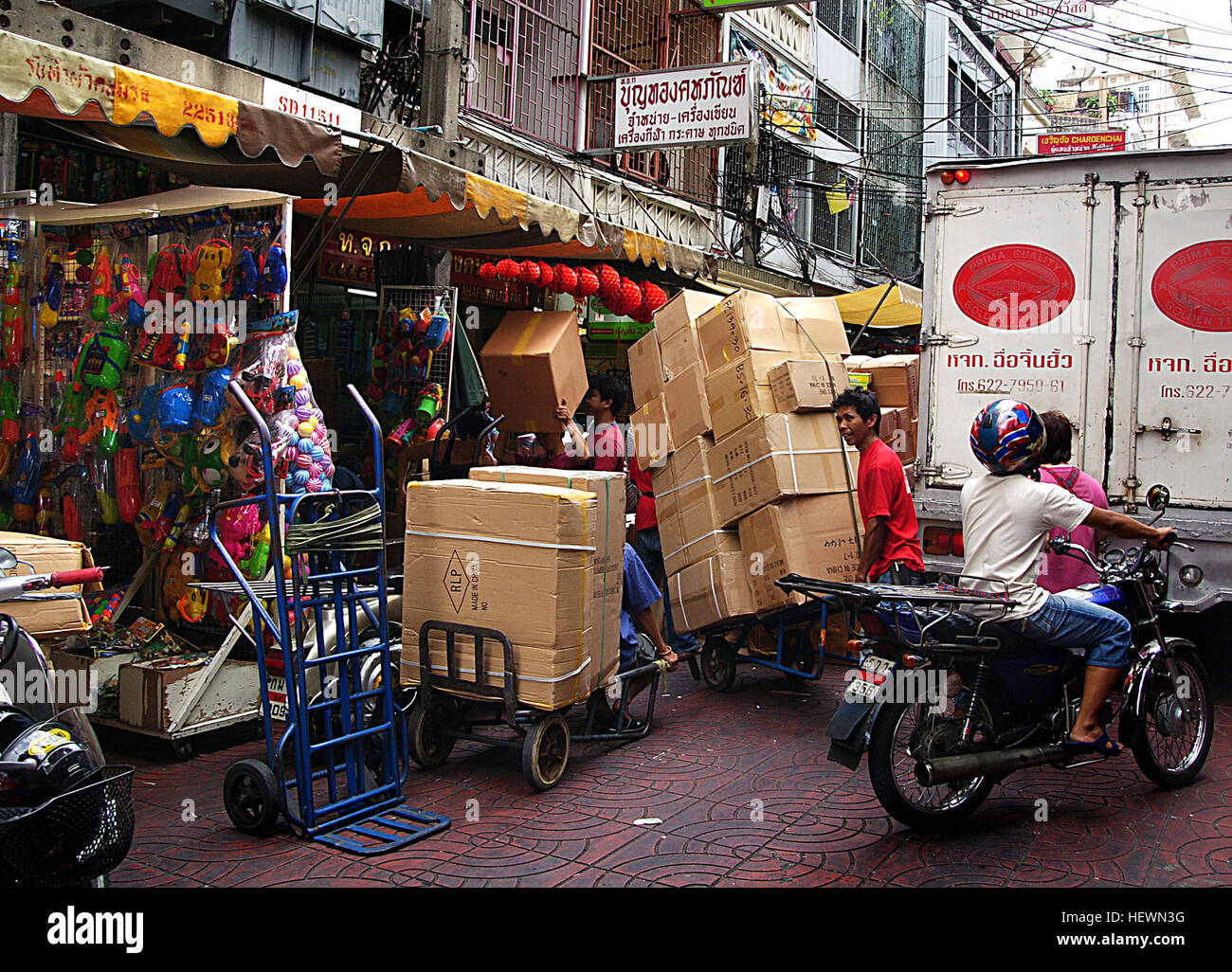 Questa immagine cattura la vivace scena delle vivaci strade di Bangkok, con moto che navigano nel traffico intenso. L'atmosfera dinamica della città è rappresentata attraverso le sue strade trafficate, piene di motociclette, scatole sovraccaricate e il ritmo vivace della vita urbana in Asia. Foto Stock