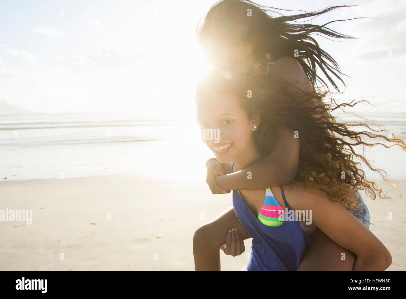 Ritratto di giovane donna femmina piggybacking amico sulla spiaggia, Cape Town, Sud Africa Foto Stock