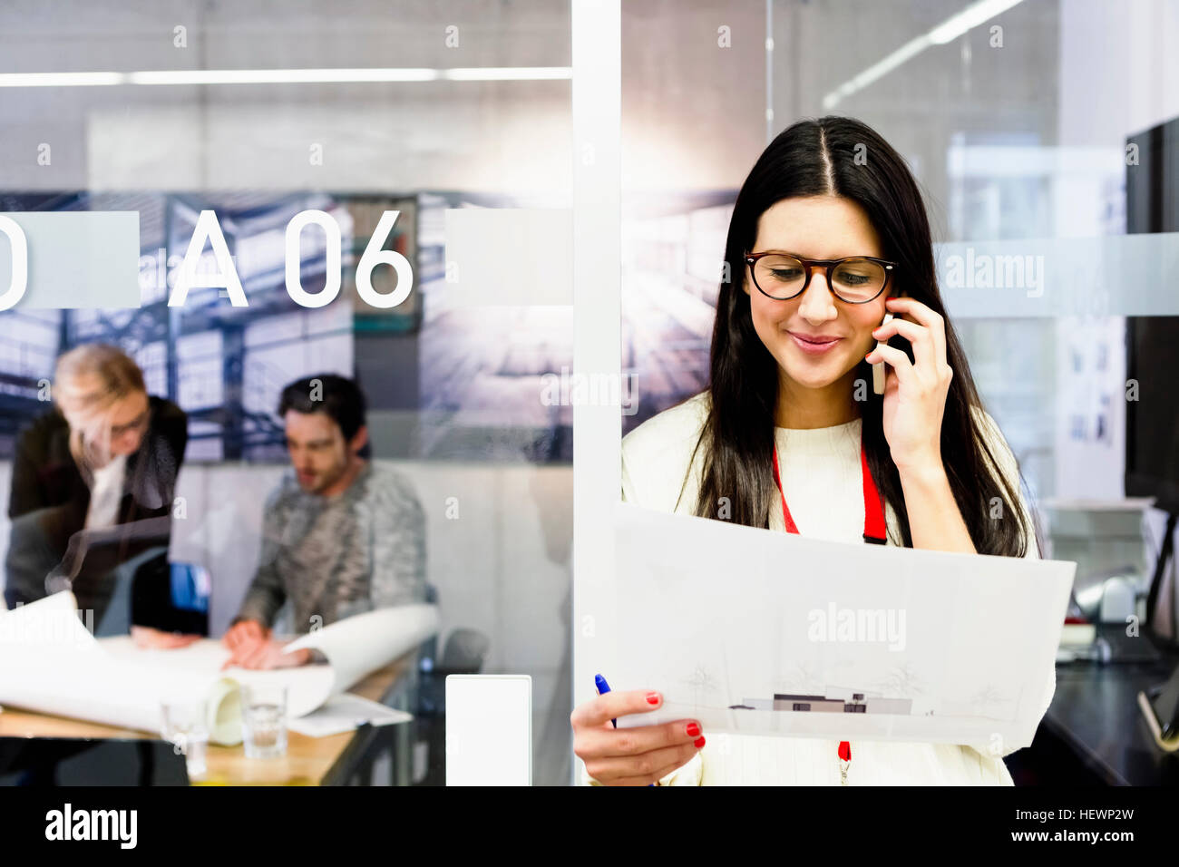 Giovane donna in office azienda pratiche utilizzando telefono mobile Foto Stock