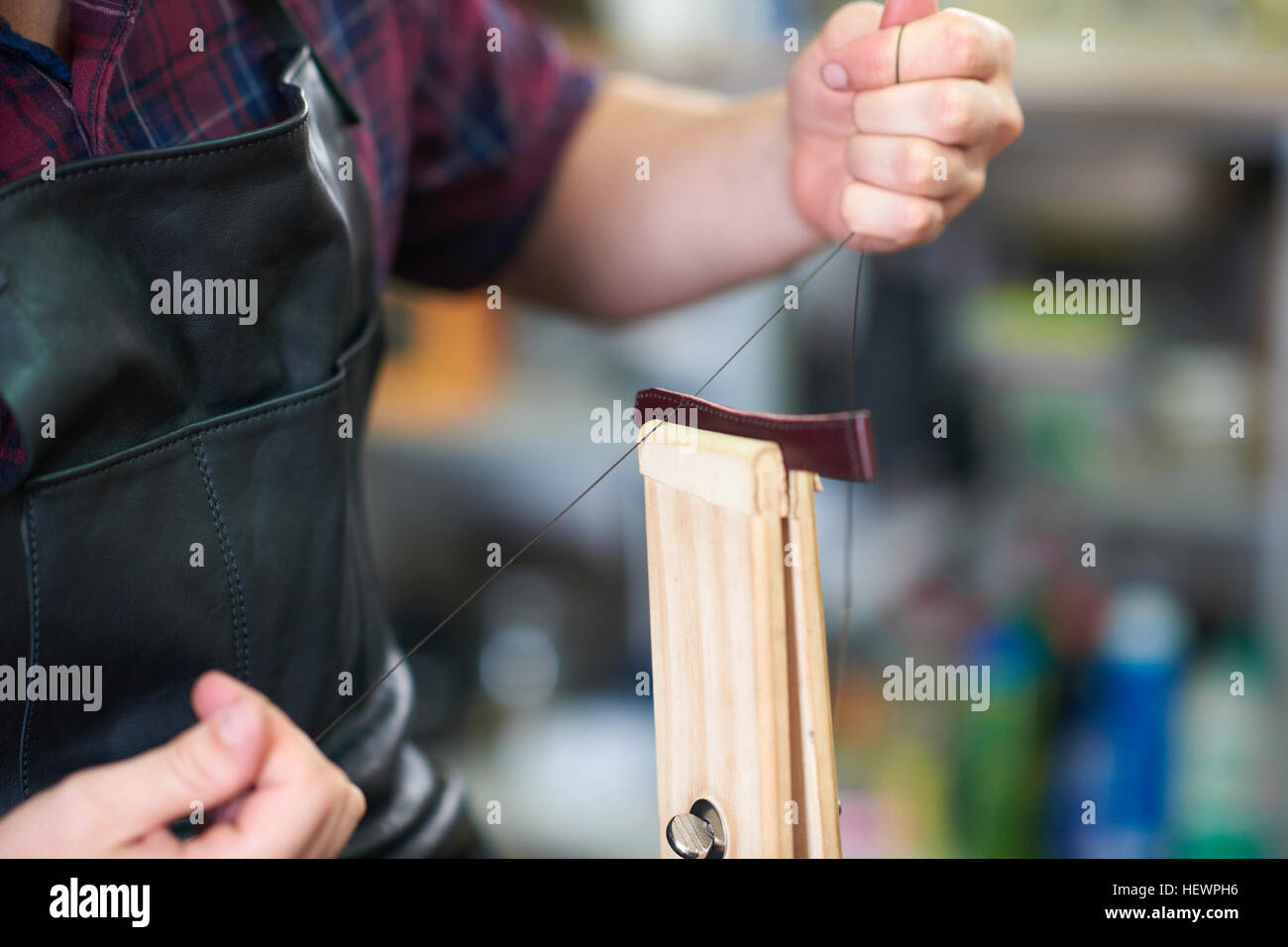 Lavoratore di sesso maschile in officina in pelle, cucitura fino cinturino, metà sezione, close-up Foto Stock