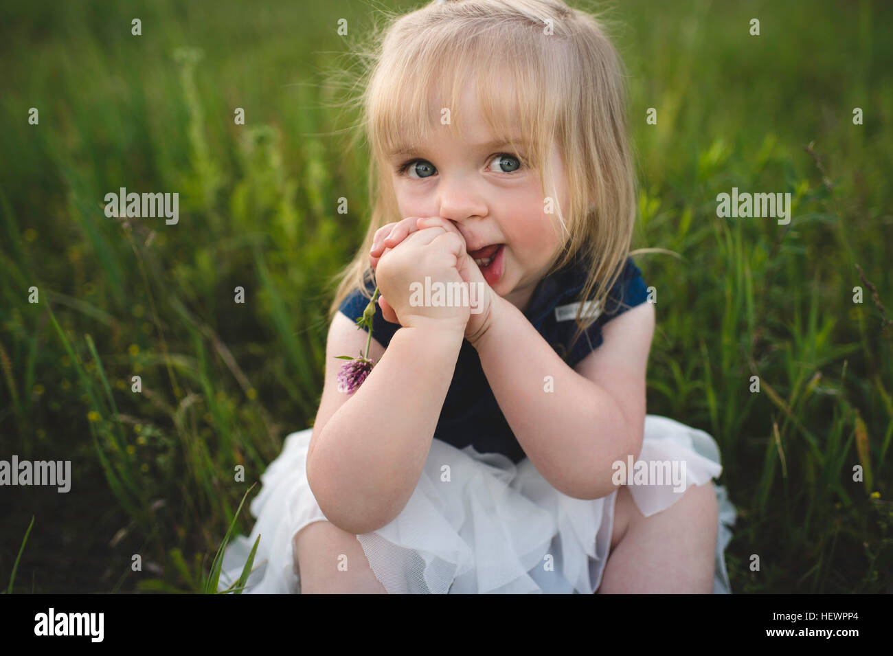 Ritratto di ragazza seduta su erba guardando la fotocamera Foto Stock