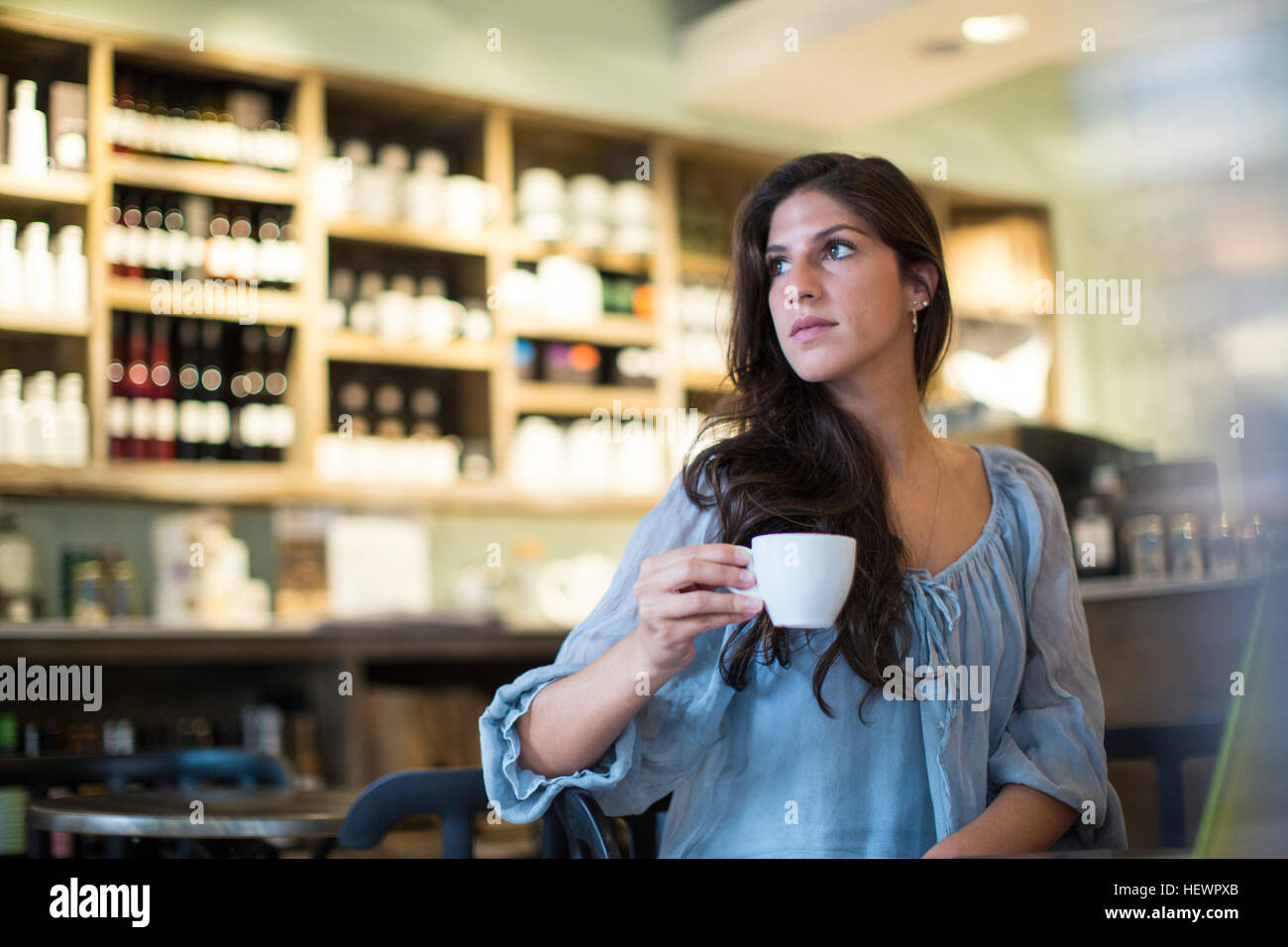 Giovane donna seduta al cafe guardando lateralmente Foto Stock
