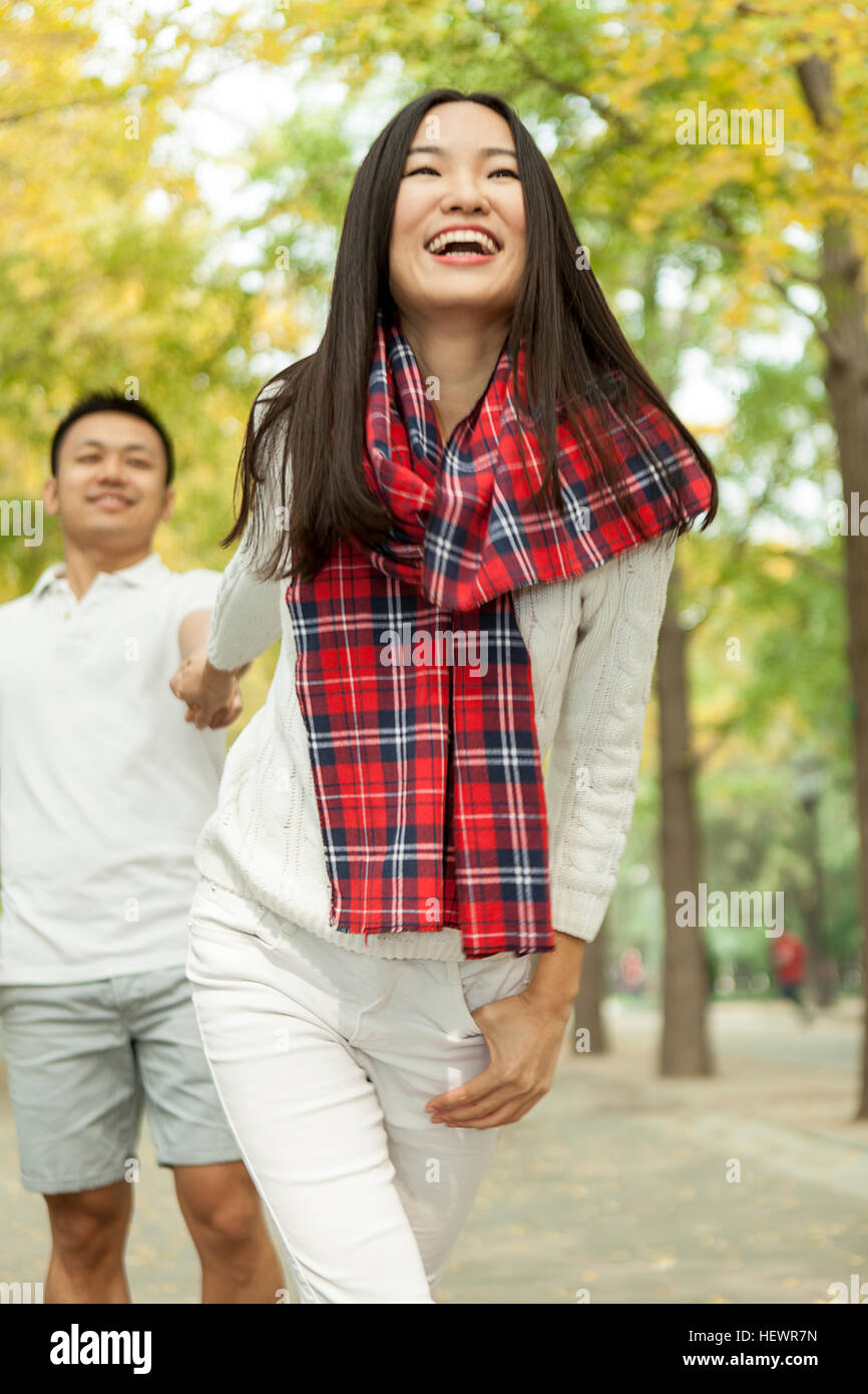 Giovane donna tirando il fidanzato per mano in autunno park, Pechino, Cina Foto Stock