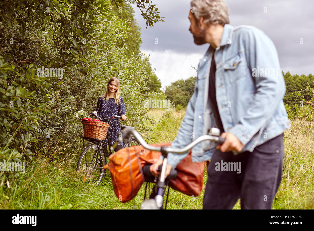 Ciclista maschio guardando indietro alla ragazza sul percorso rurale Foto Stock