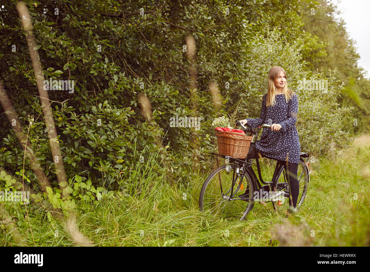 Giovane donna in bicicletta guardando sopra la sua spalla dal percorso rurale Foto Stock