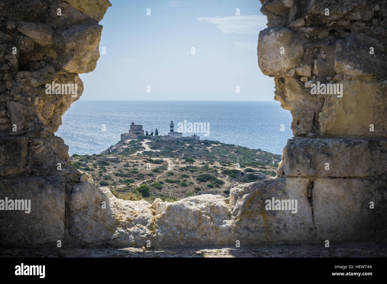 Vista del faro attraverso il foro nel muro di pietra, Cagliari, Masua, Sardegna, Italia Foto Stock