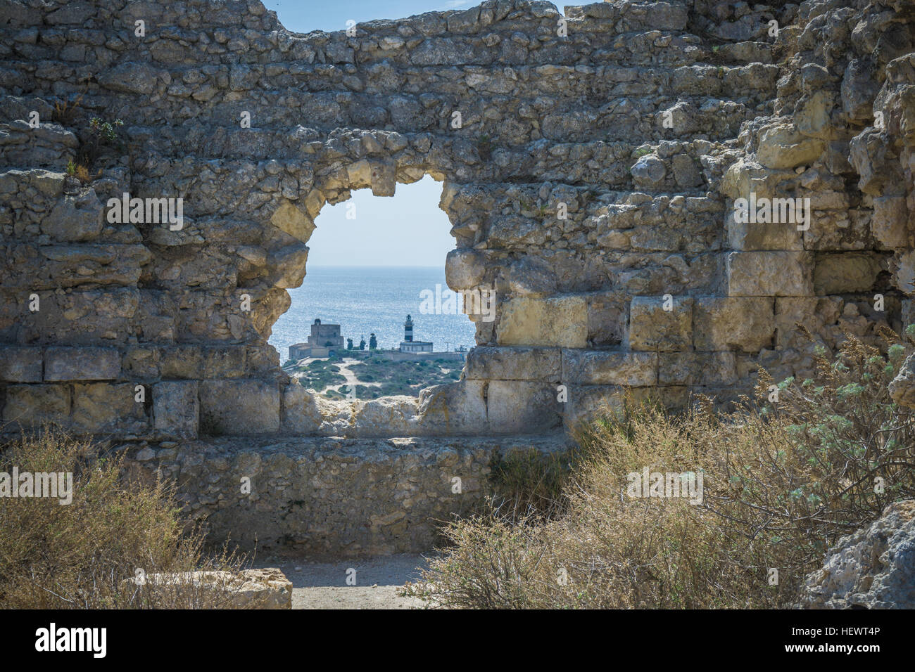Vista del faro attraverso il foro nel muro di pietra, Cagliari, Masua, Sardegna, Italia Foto Stock
